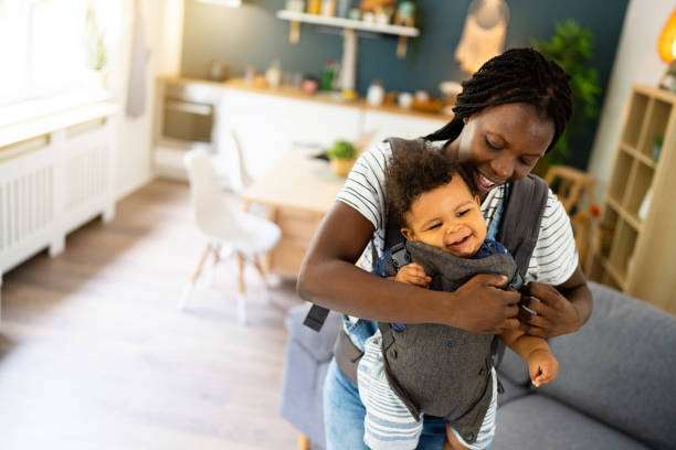 Mom is having fun playing with her baby in a baby carriers.