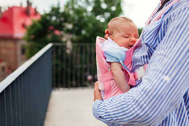 Infant girl sleeping in baby carrier.