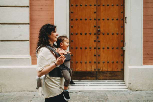 The mother is carrying the child with a baby carrier.