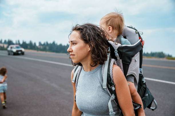 woman carrying her  son in a baby carrier 