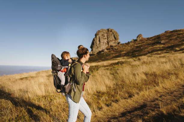 A mother takes her baby hiking in a baby carrier.