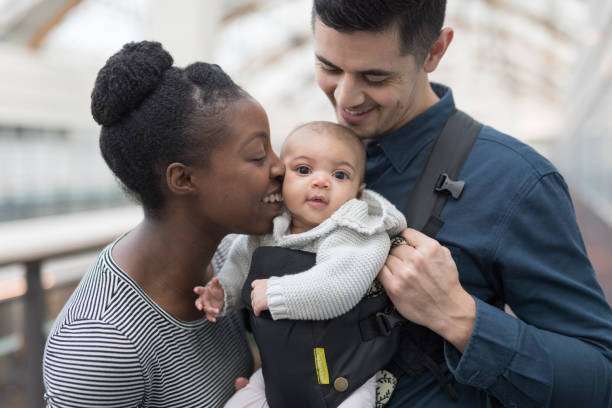 they baby daughter, who is riding in a baby carrier