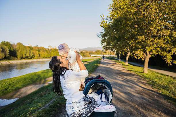 Mother is carrying her daughter in baby carrier during walk