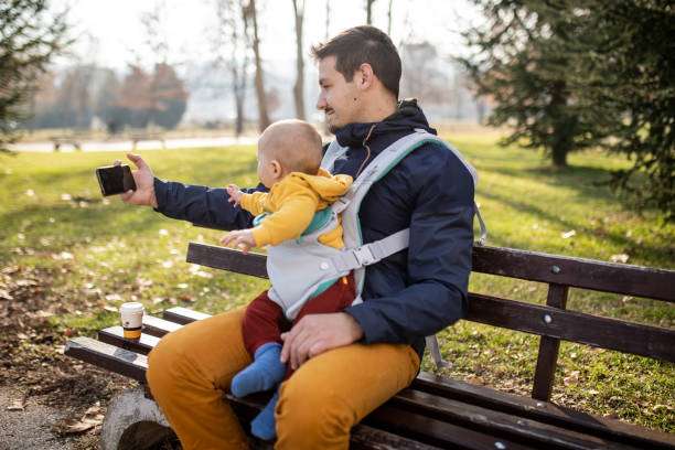Beard handsome man with his baby boy son in a baby carrier