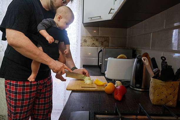 Father Cooking with his daughter in baby carrier