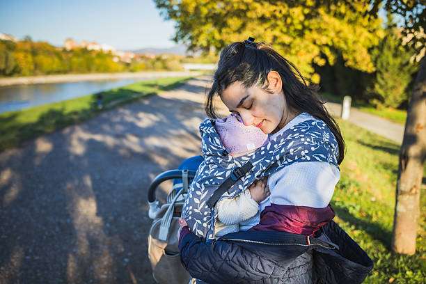 Mother is carrying her daughter in baby carrier