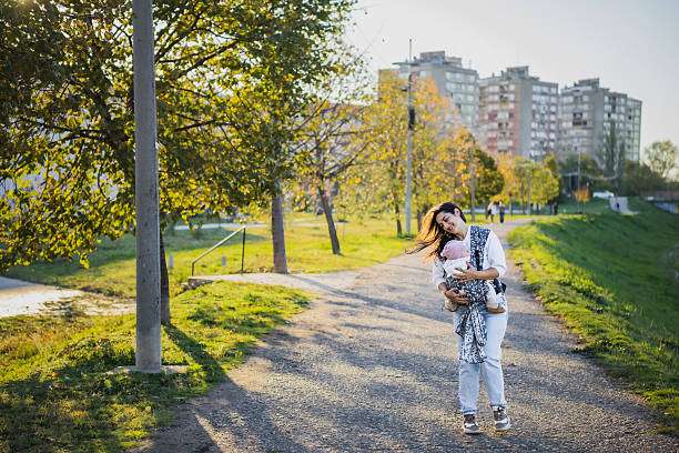 Mother is carrying her daughter in baby carrier