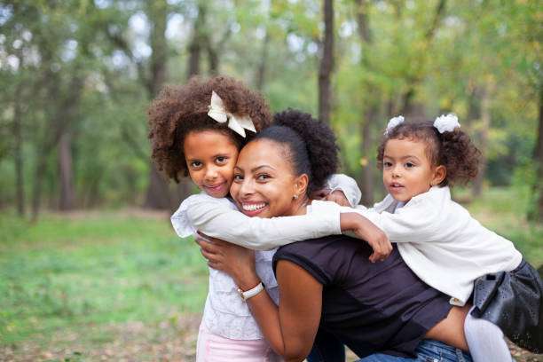 Happy woman looking to distance while holding and carrying it in a baby carrier in a park
