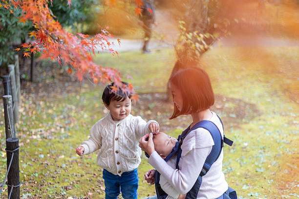 Happy woman looking to distance while holding and carrying it in a baby carrier in a park