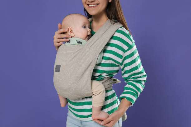 Cheerful young mother with a big smiling baby carrier her cute child