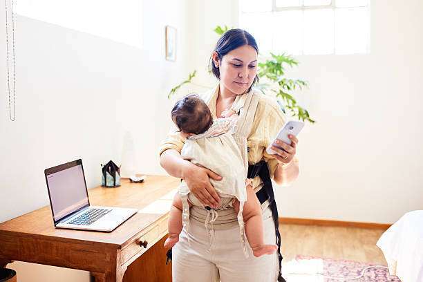 her office desk, using a computer while carrying her baby carrier.