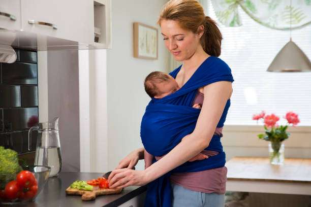 Cheerful young mother with a big smiling baby carrier her cute child