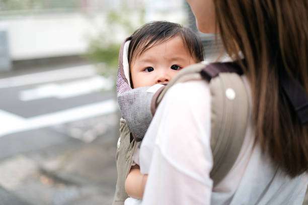 A contented mother looking at camera baby carrier her young child