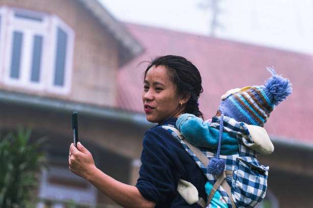 A contented mother looking at camera baby carrier her young child