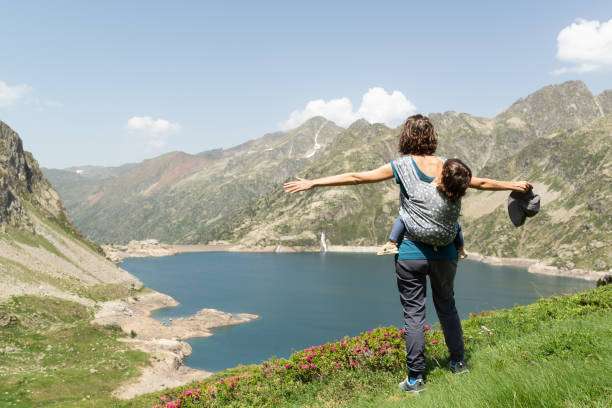 Profile of a mother standing while carrying a baby on her back in a baby carrier outdoors