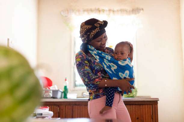 Cheerful young mother with a big smiling baby carrier her cute child