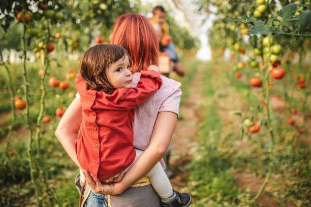 Profile of a mother standing while carrying a baby on her back in a baby carrier outdoors