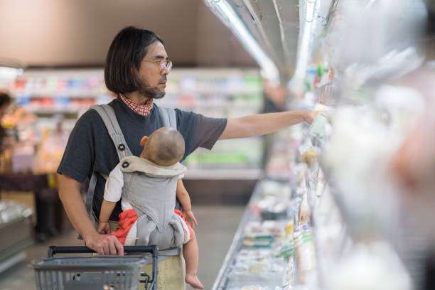 A father is doing shopping while carrying his baby boy in a supermarket.baby carrier
