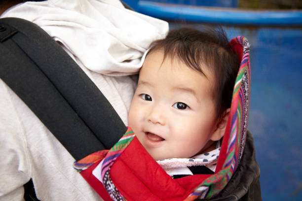 her daughter in baby carrier at home