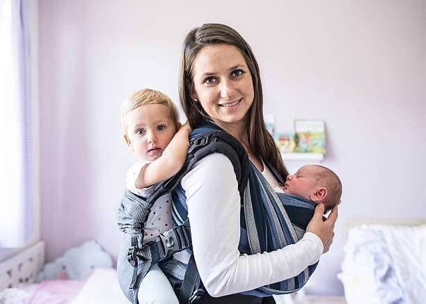 her daughter in baby carrier at home