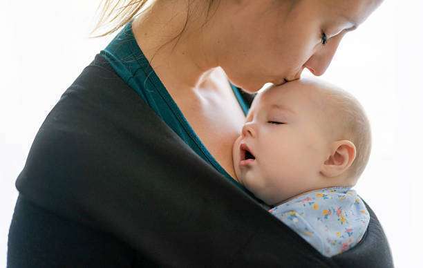 A young mother with her daughter in sling Baby Carrier