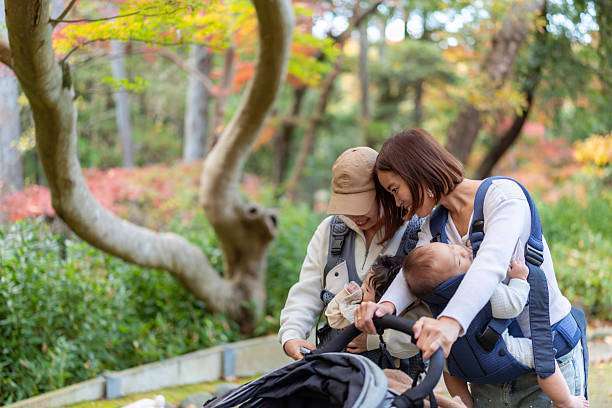 Happy woman looking to distance while holding and carrying it in a baby carrier in a park
